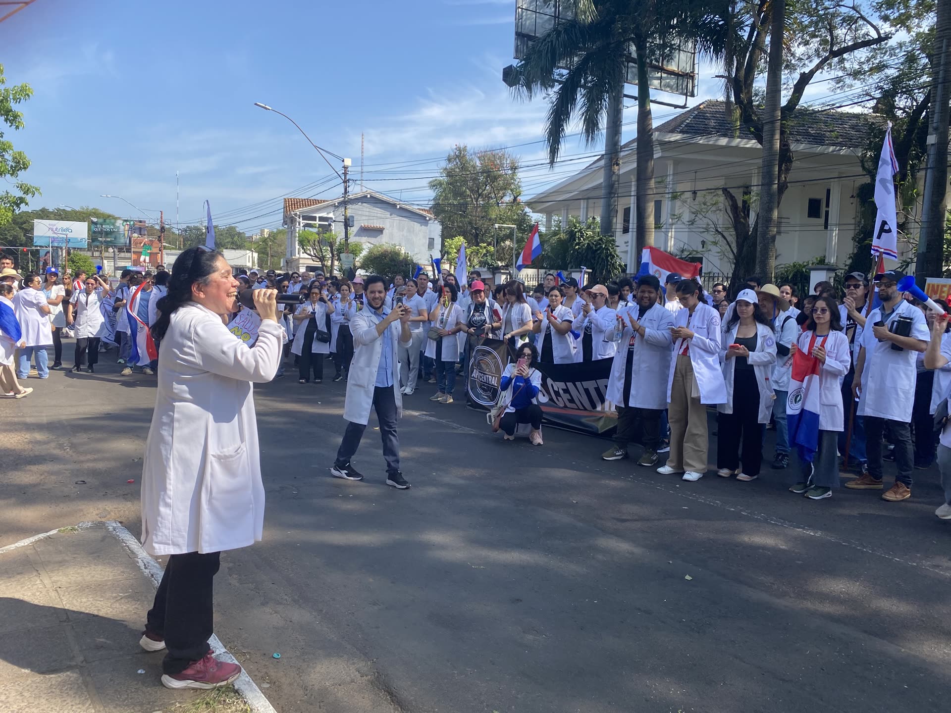 Médica de SINAMED liderando un cántico con megáfono ante colegas movilizados